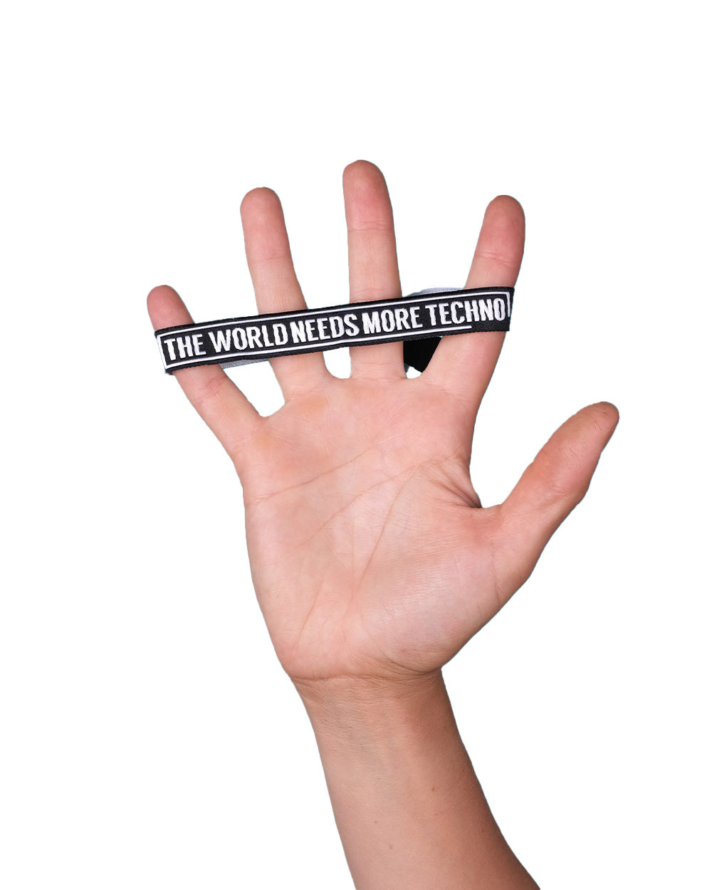 Hand stretches black wristband with the text "The World Needs More Techno" across fingers.